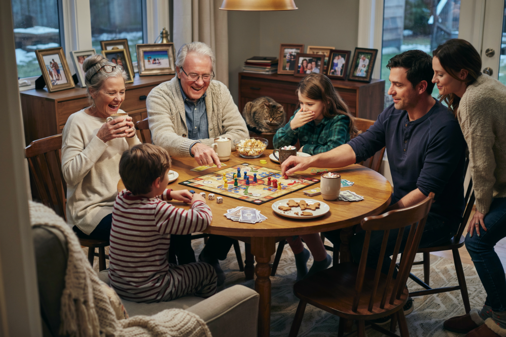 Großeltern, Eltern und Kinder verbringen gemeinsam einen gemütlichen Brettspielabend und schaffen wertvolle Familienerinnerungen.