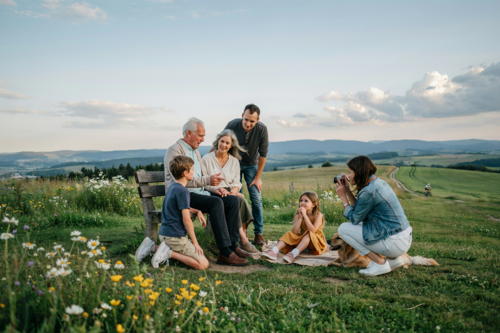 Familie mit Kindern und Großeltern genießt gemeinsam die Aussicht an einem besonderen Lieblingsort und schafft neue Erinnerungen.
