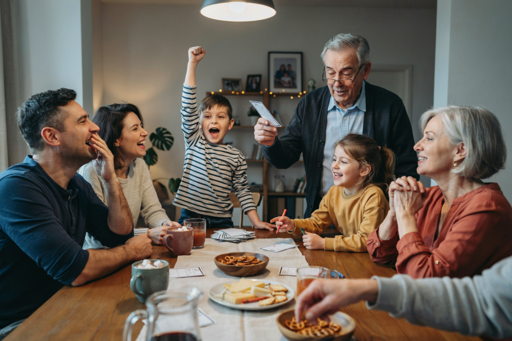 Familie mit Kindern und Großeltern spielt gemeinsam ein Quizspiel und verbringt einen fröhlichen Abend voller Spaß und Gespräche.