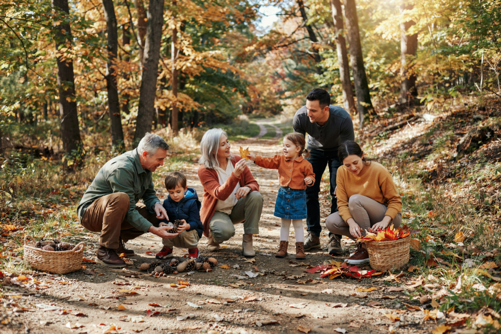 Familie sammelt gemeinsam Tannenzapfen und bunte Blätter bei einem Waldtag und entdeckt die Natur mit Kindern.